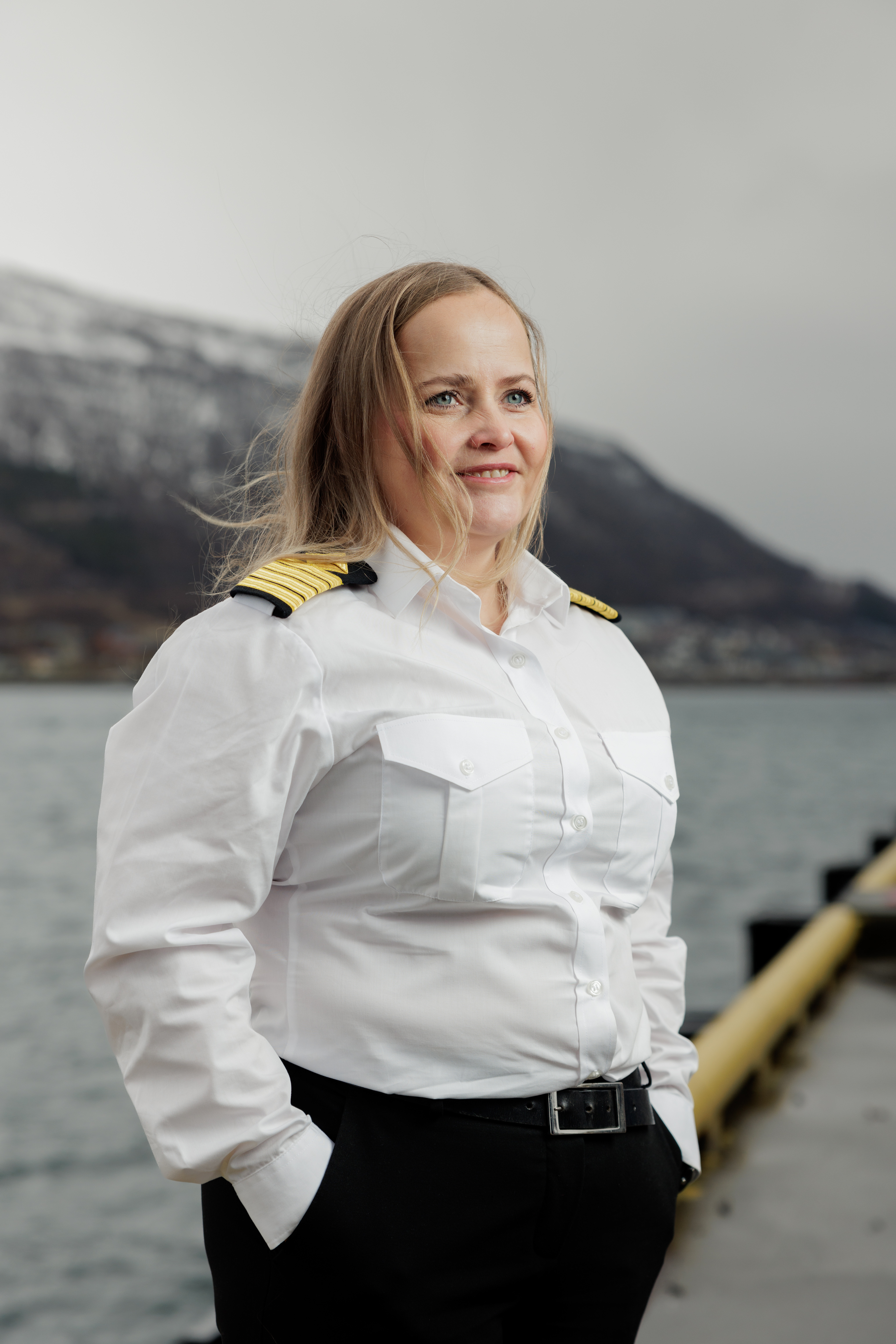 Portrait of female Odfjell officer standing by the harbor with mountains in the background.