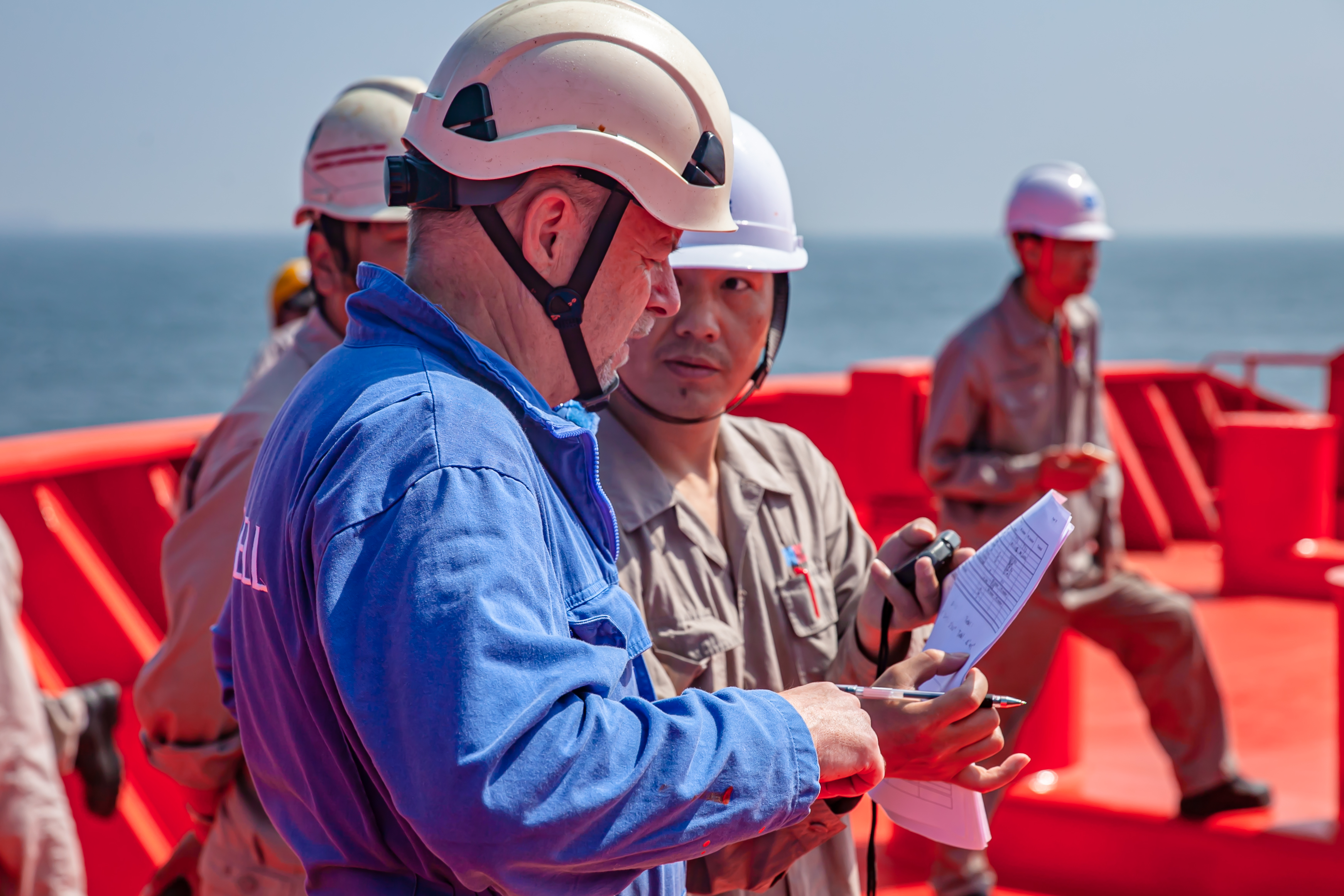 Odfjell seafarers conduct a safety briefing on deck, reviewing procedures and coordinating tasks under clear sea conditions.