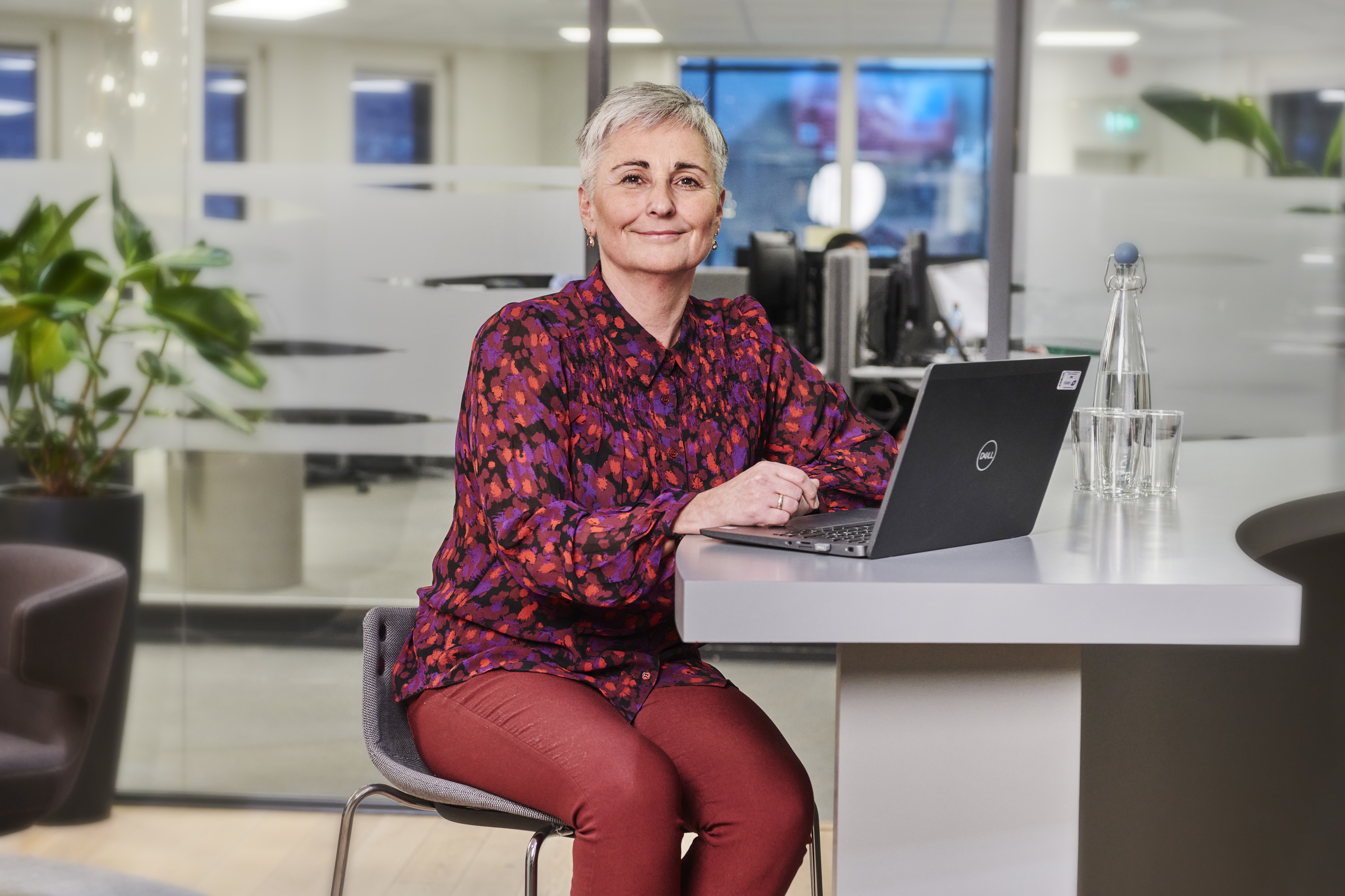 An operator sits confidently in a modern office environment, working at a laptop with a calm and professional presence.