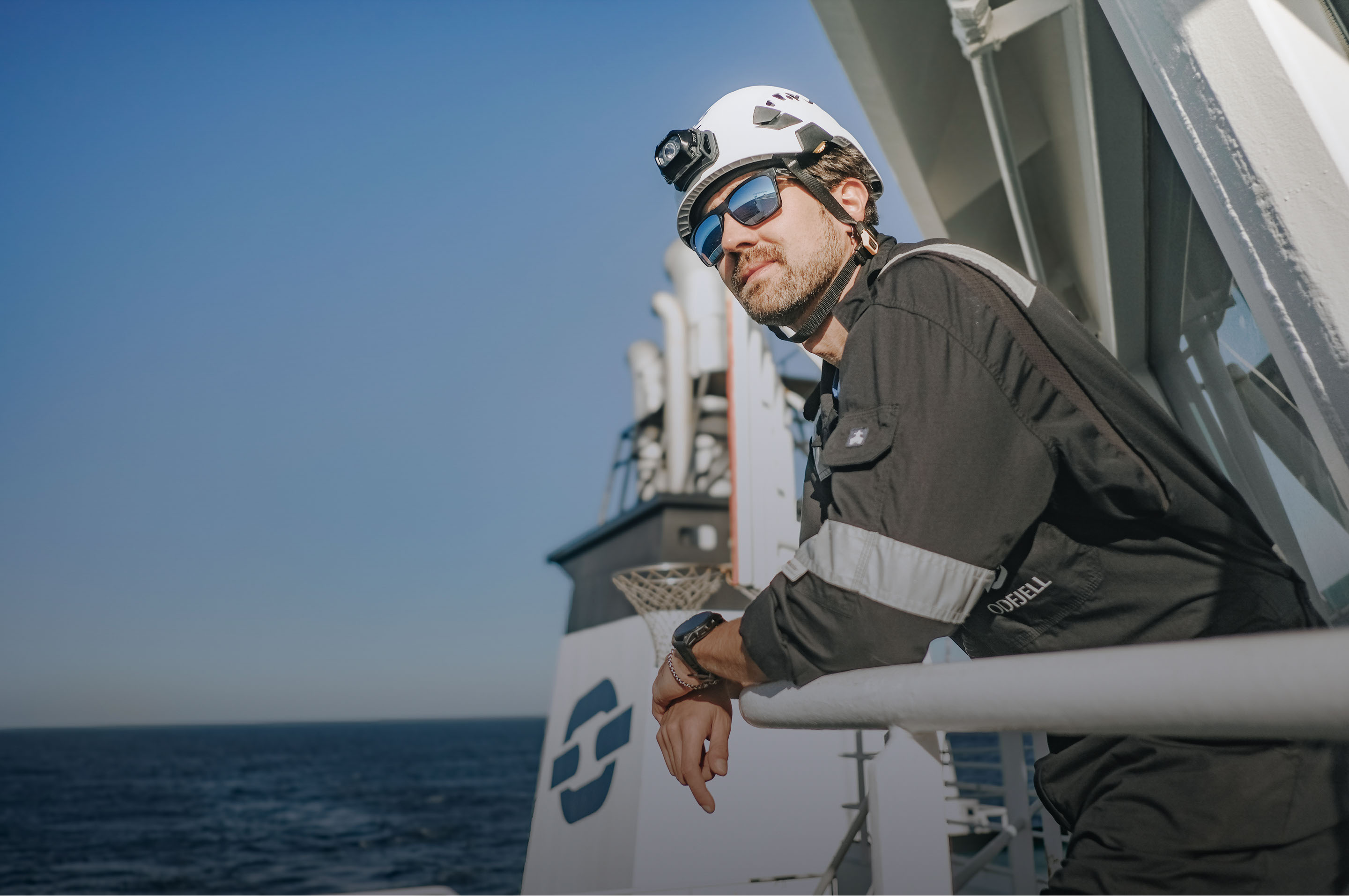 Odfjell crew member standing on deck near the ship funnel, overlooking the ocean.