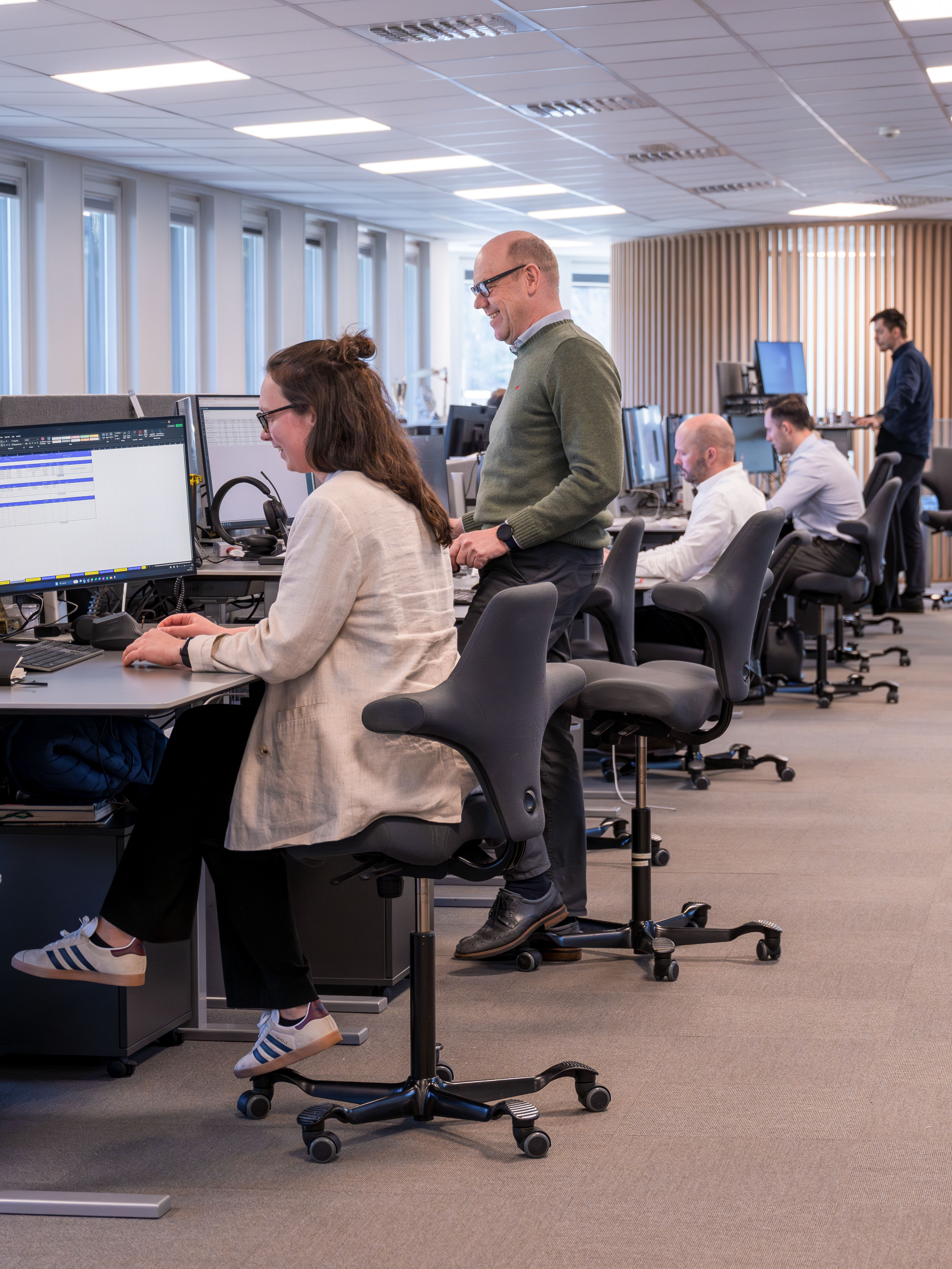 Odfjell office employees discussing and analyzing data in collaborative workspace.