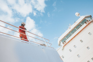 Odfjell crew member performing maintenance work on deck under clear blue sky.