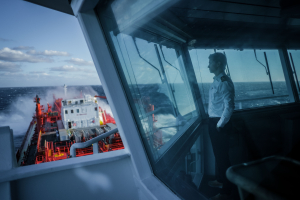 Odfjell officer standing on the bridge watching waves hit the chemical tanker at sea.