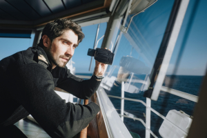 Odfjell navigator observing the horizon through binoculars on the ship’s bridge.