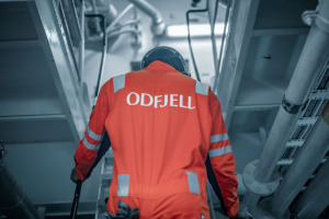 Odfjell crew member wearing orange uniform working inside the ship’s engine room.