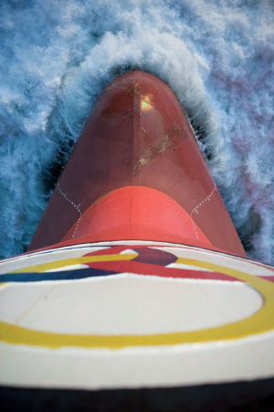 Aerial view of an Odfjell tanker’s bow cutting through ocean waves, showing the company logo and ship in motion.