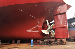 Odfjell employee inspecting ship propeller and rudder during drydock maintenance.