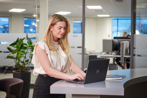 Odfjell employee working on laptop in modern open-plan office environment.