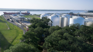 Aerial view of Odfjell terminal with chemical storage tanks, railway tracks and a tanker vessel docked by the port.