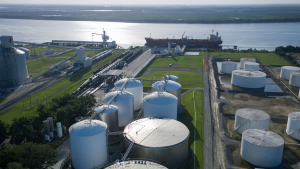 Wide aerial shot of Odfjell tank terminal near a river dock with green surroundings and moored tanker ship.