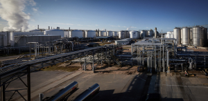 Wide view of Odfjell terminal showing pipelines, steam, and chemical storage tanks under clear sky.